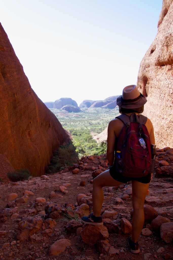 Sarah looking over the landscape through two sandstone formations at kata tjuta.