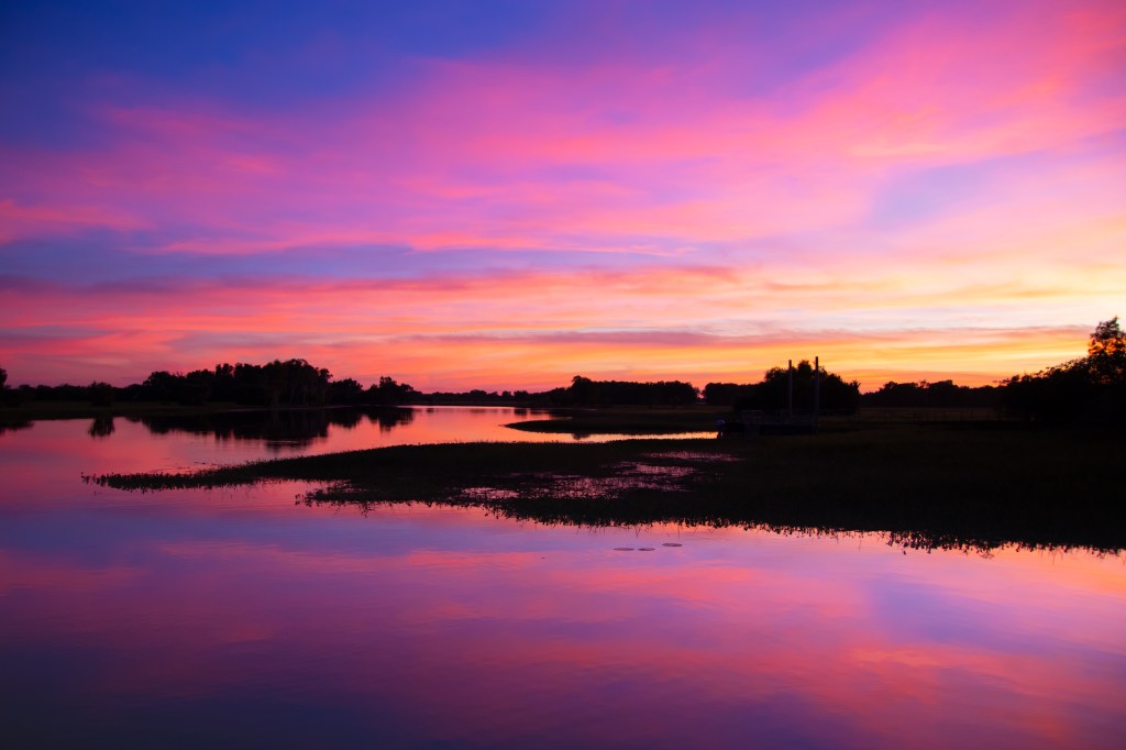 Reflection of a pink and purple sunrise sky at yellow waters billabong.