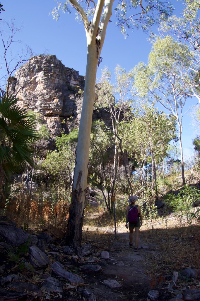 Sarah walking along a path towered by sandstone formations.