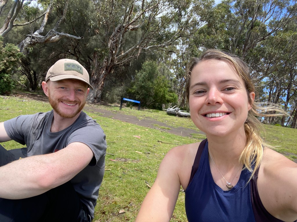 A smiley selfie of Sarah and George on a large patch of grass.